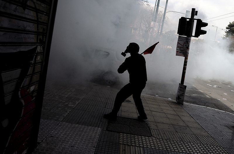 Un manifestante con máscara antigás se enfrenta con los policías antidisturbios.