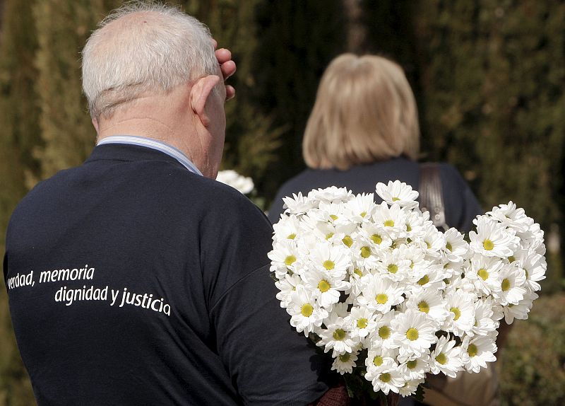 Un hombre lleva un ramo de flores para despositar en la ofrenda floral en el Bosque del Recuerdo