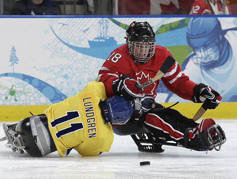 El jugador candiense Bridges lucha con el jugador sueco Lundgren en el partido de hockey sobre hielo de los Paralímpicos de Vancouver.