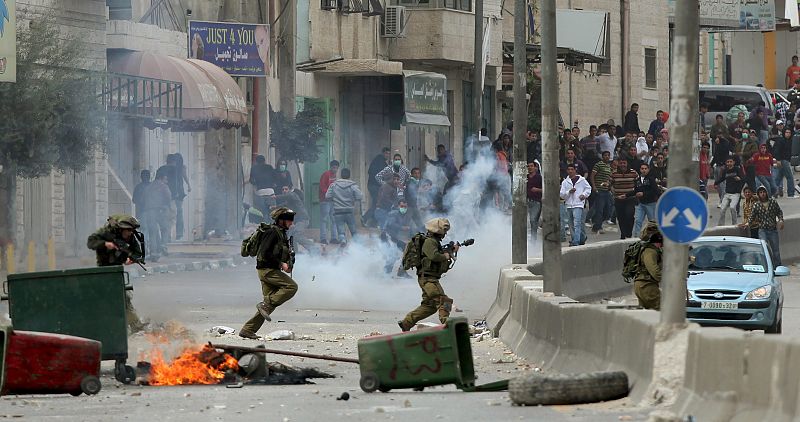 Unos jóvenes palestinos arrojan piedras a un grupo de policías israelíes en el puesto de control de Kalandia, entre Jerusalén y Cisjordania,