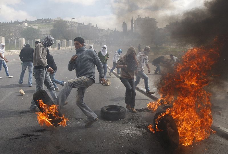 Jóvenes palestinos queman y patean neumáticos durante los violentos disturbios contra tropas israelíes en Jerusalén Este.