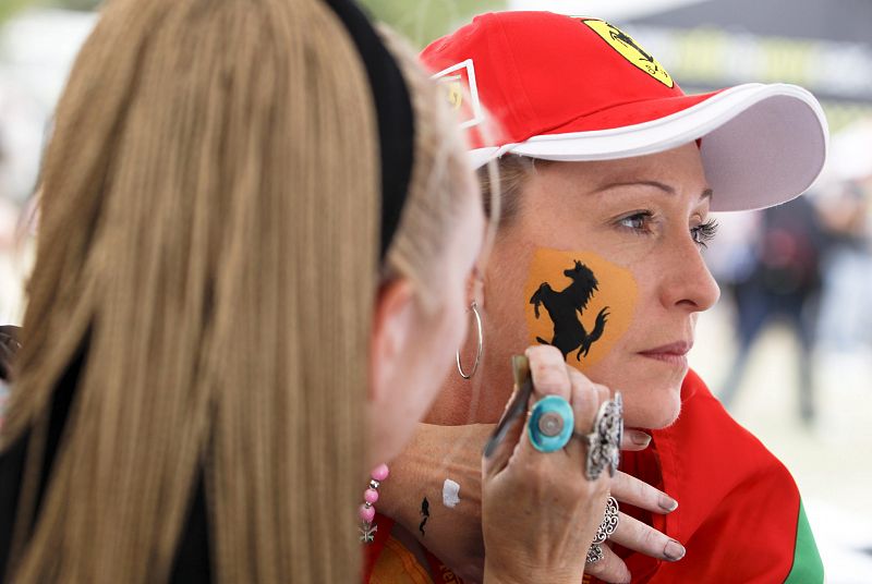 Una mujer pinta su cara con el logo de la escudería Ferrari antes del GP de Australia.