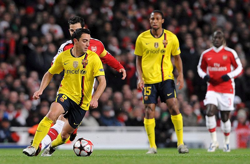 El centrocampista del FC Barcelona Xavi Hernández escapa con el balón de Cesc Fábregas.