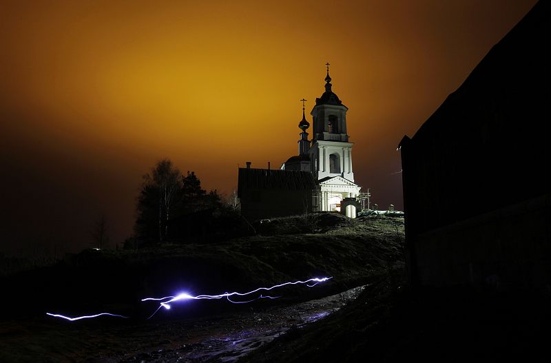 A man uses a torch as he leaves a church after an Orthodox Easter night mass in the settlement of Roshcha