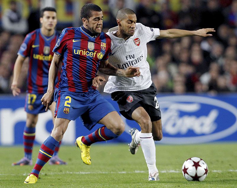 El defensa brasileño del FC Barcelona Daniel Alves y el defensa francés del Arsenal, Gael Clichy luchan por la pelota.