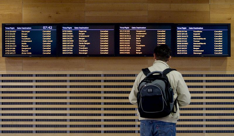 Un viajero mira los paneles informativos del aeropuerto de Oslo con todos los vuelos supendidos