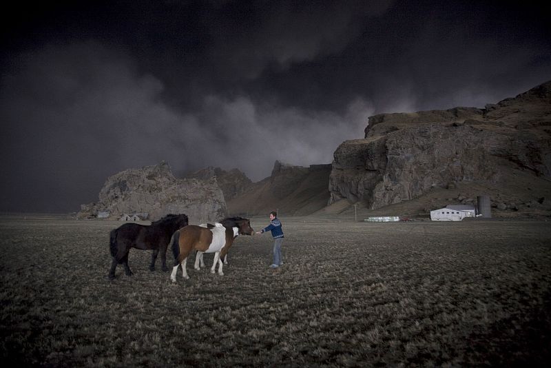 Farmer Thorarinn Olafsson tries to lure his horses back to the stable as a cloud of black ash looms overhead in Drangshlid 2 at Eyjafjoll