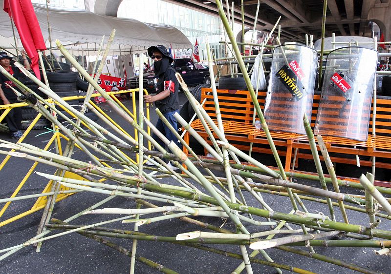 Un manifestante vigila desde una barricada hecha con bambú y neumáticos.
