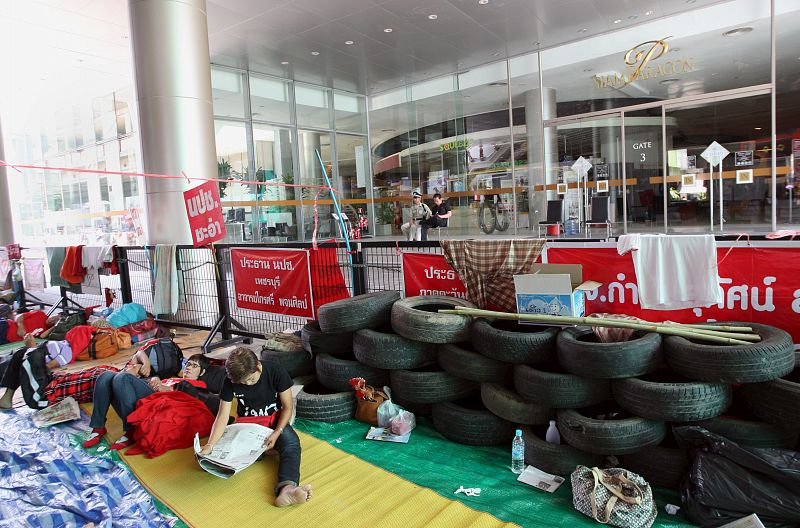 Varios manifestantes antigubernamentales descanas junto a una barricada montada en los alrededores de un centro comercial