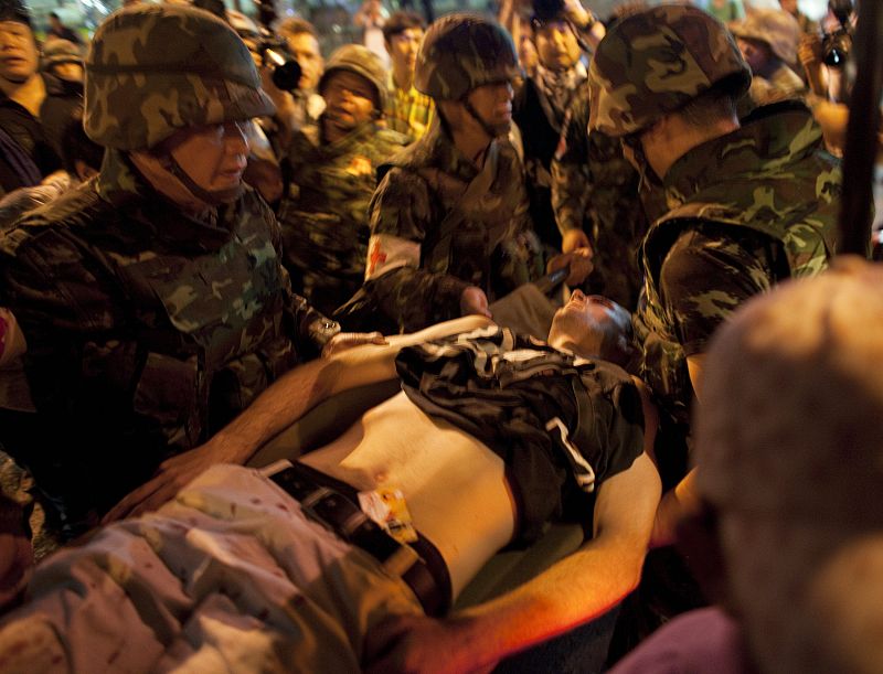 Thai army paramedics rush an injured man to an ambulance after explosions shook the Silom Road area in Bangkok