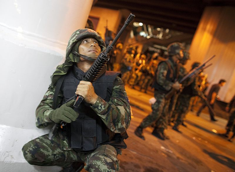 Thai army soldiers take position along the road after multiple explosions near pro-government supporters rallying in Bangkok's Silom business district