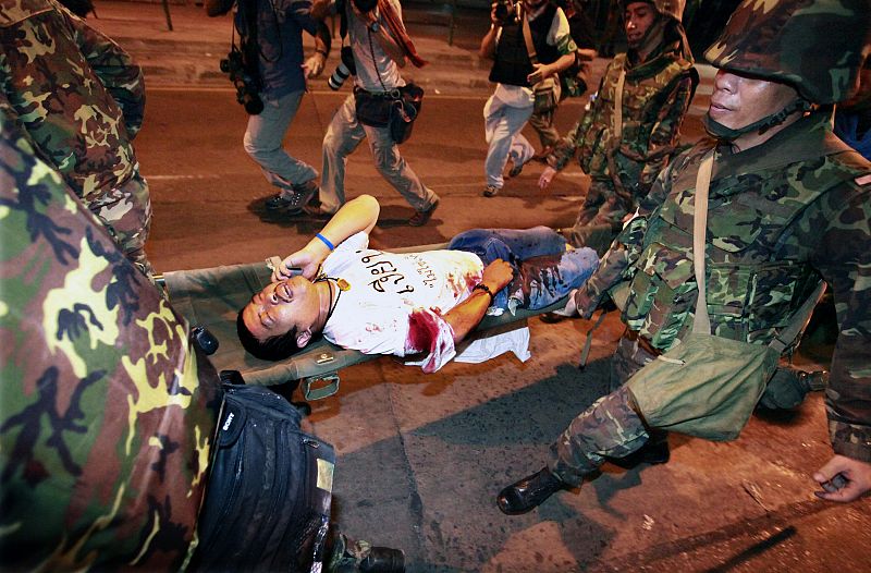 Thai soldiers carry an injured man following several small explosions in the business district of Bangkok