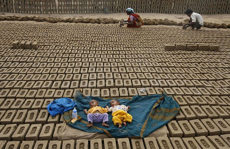 Labourers work as their children sleep at a brick factory on the outskirts of Jammu