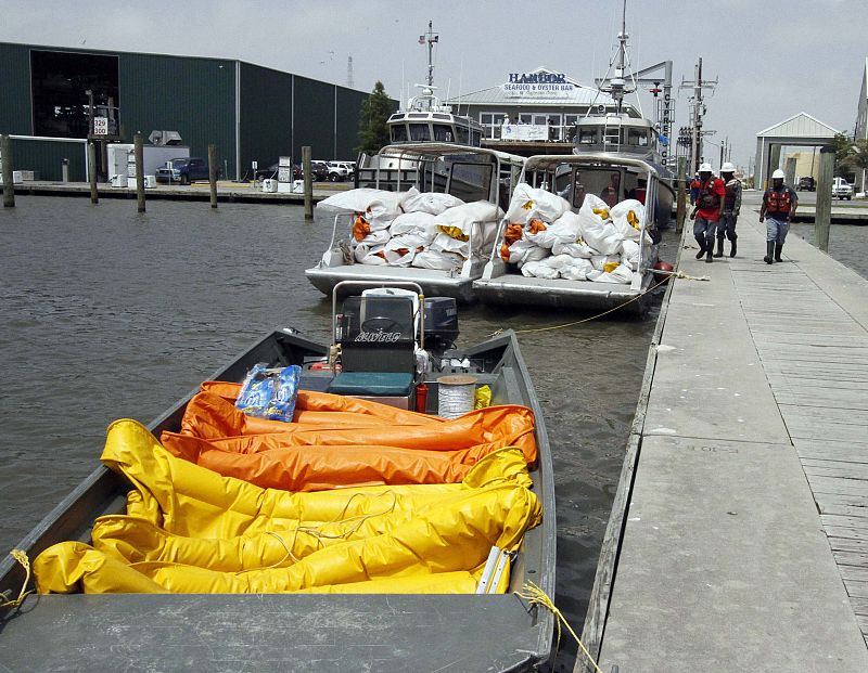 Workers walk by boats loaded with the booms local fisherman are going to deploy in an effort to contain the oil spill in the Gulf of Mexico in Venice