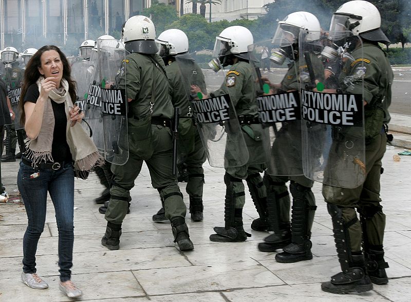 Una mujer huye asustada de los enfrentamientos de este miércoles entre la policía antidisturbios y los manifestantes.