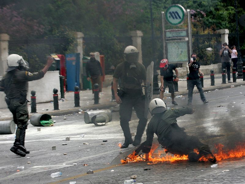 Agentes de la policía antidisturbios reciben el impacto de un cóctel molotov durante un acto de protesta frente al Parlamento griego en Atenas.
