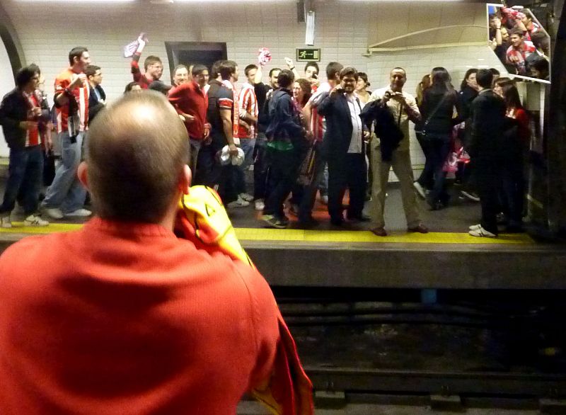 Un grupo de aficionados del Atlético celebran la victoria de su equipo en un andén del metro de Madrid.