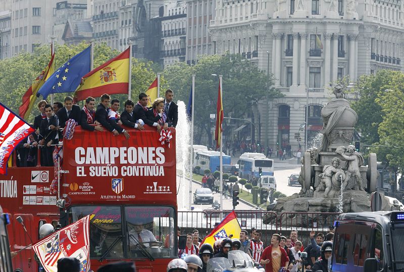 Los jugadores del Atlético de Madrid, subidos a un autobús descubierto, a su paso junto a la fuente de La Cibeles.