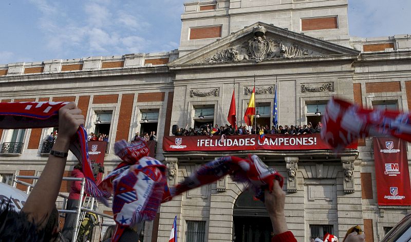 Los jugadores y equipo técnico del Atlético de Madrid saludan a los aficionados desde el balcón de la sede de la Comunidad.