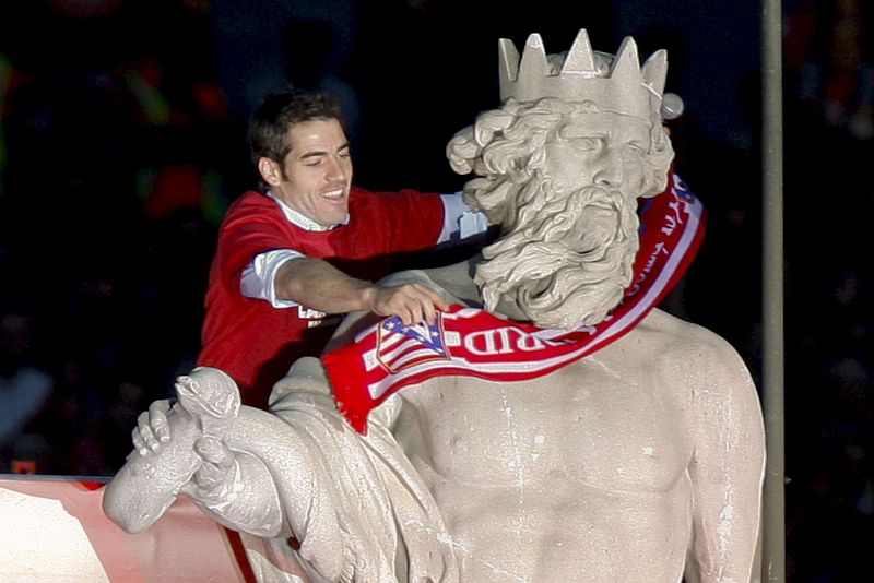 El defensa del Atlético de Madrid Antonio López coloca la bufanda del club en la estatua de Neptuno
