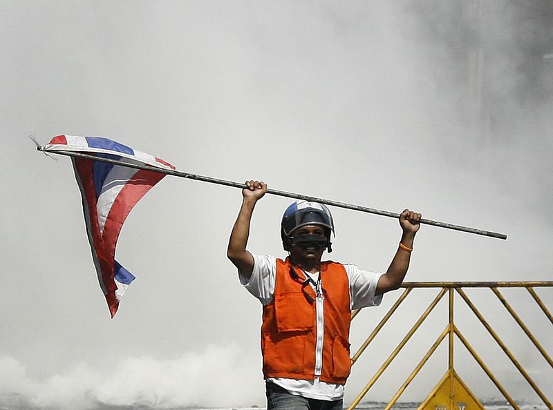 Un manifestante sostiene la bandera tailandesa en medio de los disturbios