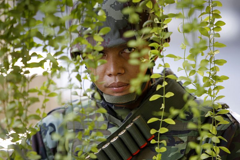 A soldier keeps watch near the perimeter of the barricaded anti-government 'red shirt' encampment at Bangkok's shopping district