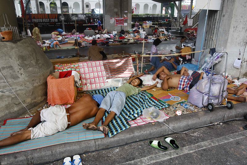 Protesters sleep on the sidewalks of the barricaded anti-government "red shirt" encampment in Bangkok's shopping district