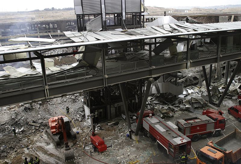 Spanish firemen and cleaning crews remove the debris at one of the parking lots of Madrid's Barajas airport