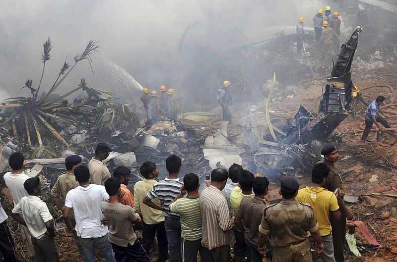 Onlookers and firefighters stand at the site of the crashed Air India Express passenger plane in Mangalore