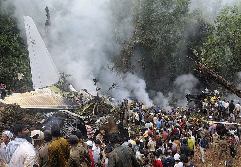 Onlookers and firefighters stand at the site of a crashed Air India Express passenger plane in Mangalore
