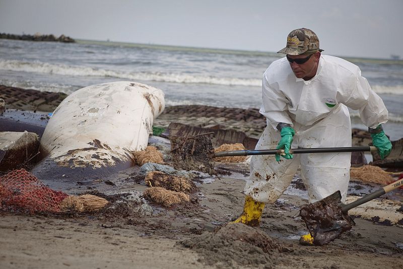 Un trabajador se afana en recoger los restos de petróleo en la orilla de una playa de Lousiana