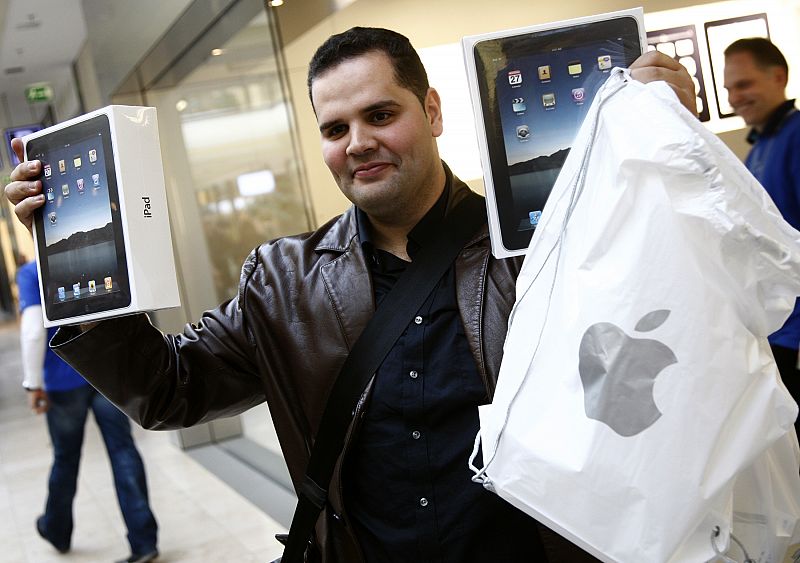 A customer poses with two Apple iPads as he leaves the Apple retail store in Hamburg