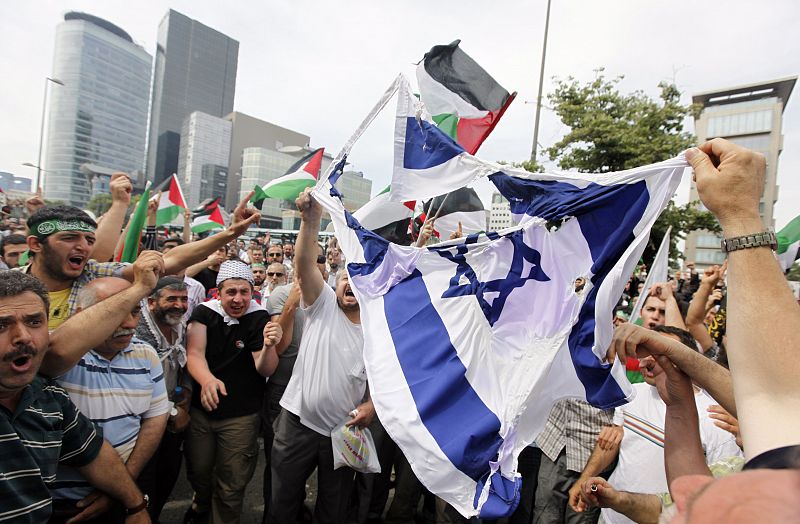 Varios manifestantes tratan de prender fuego a una bandera israelí en Estambul.