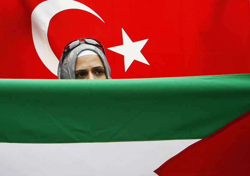 A Turkish student stands near Turkish and Palestinian flags during a protest in front of the parliament building in Sarajevo