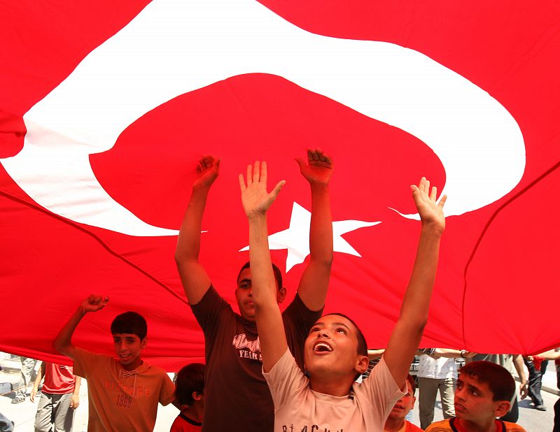 Palestinian boys walk under a Turkish flag during a protest at Gaza's seaport