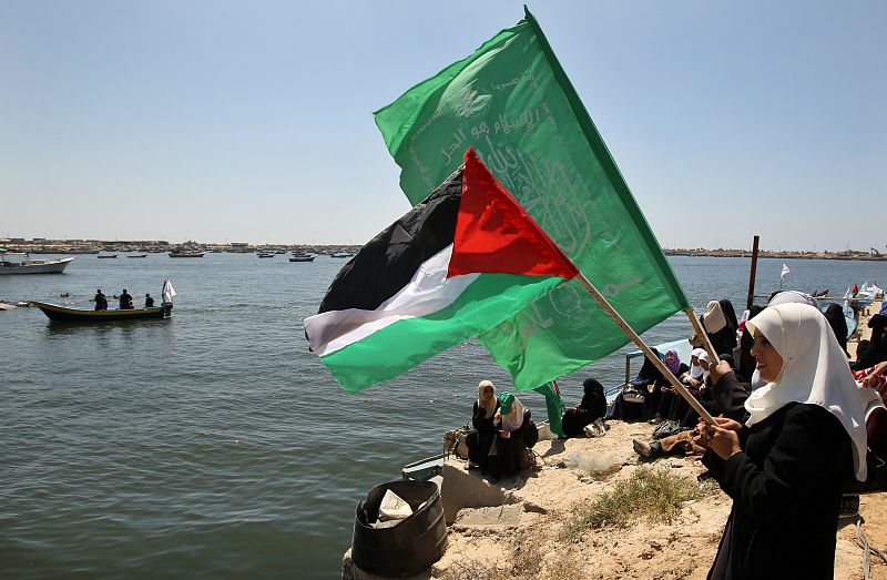 Palestinian women wave Palestinian and Hamas flags during a protest at Gaza's seaport