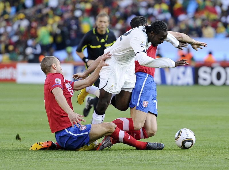 Ghana's Prince Tagoe falls after a tackle from Serbia's Dejan Stankovic and Nemanja Vidic during a 2010 World Cup Group D soccer match