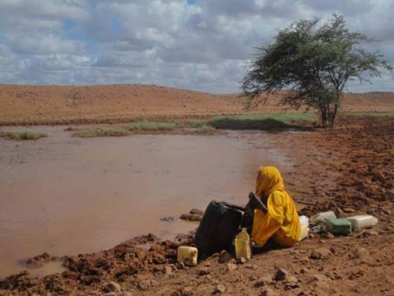 Mujer frente a una charca sucia en busca de agua, en Etiopía.