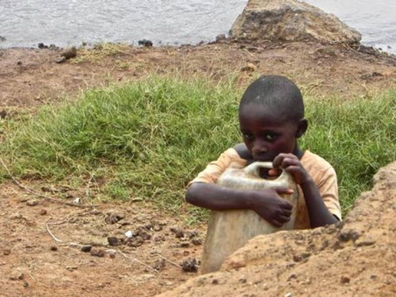 Niña con un bidón de agua enfrente de una charca a los alrededores de Kiwesi, Kenia.