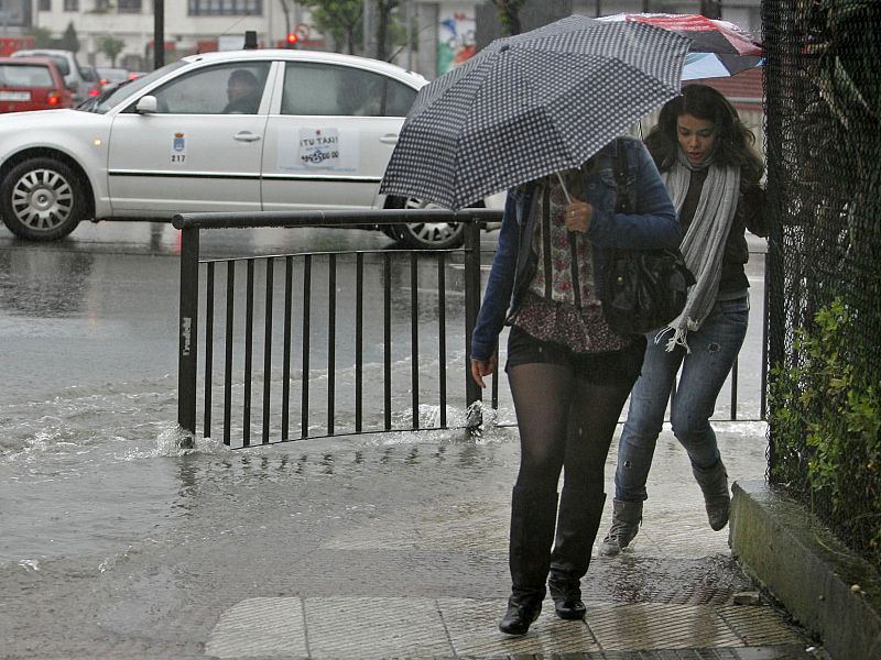 Los viandantes caminan como pueden por las calles anegadas de la capital asturiana.