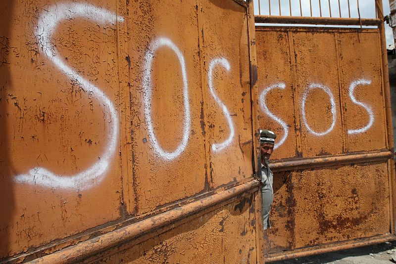 Un uzbeko mira desde un portón en el que hay escrito "SOS", en el distrito de Osh