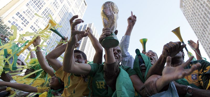 Aficionados brasileños celebran la victoria ante Corea del Norte con una réplica de la Copa del Mundo.