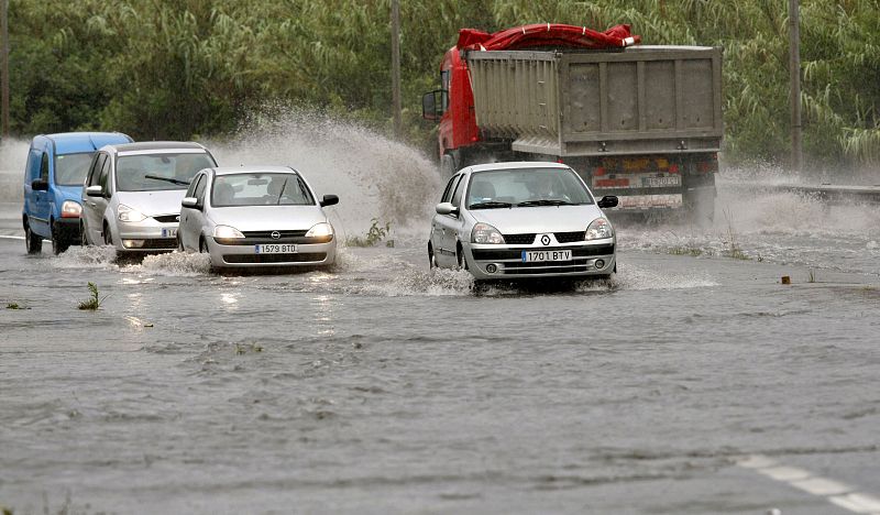 Varios vehículos atraviesan una balsa de agua en la BI-735 en el municipio vizcaíno de Erandio momentos antes de ser cortada la vía como consecuencia de las lluvias caídas en este territorio.