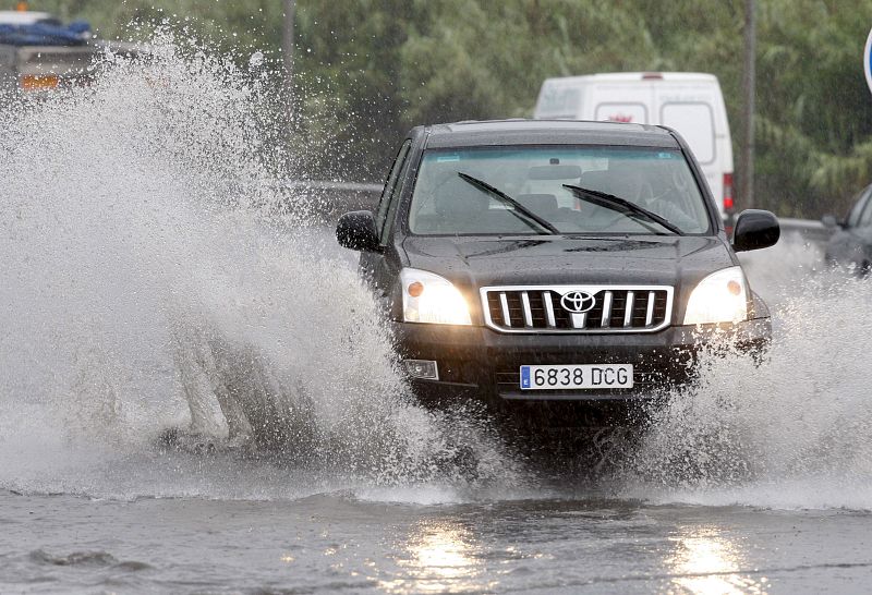Un vehículo atraviesa una balsa de agua en la BI-735 en el municipio vizcaíno de Erandio momentos antes de ser cortada la vía como consecuencia de las lluvias.