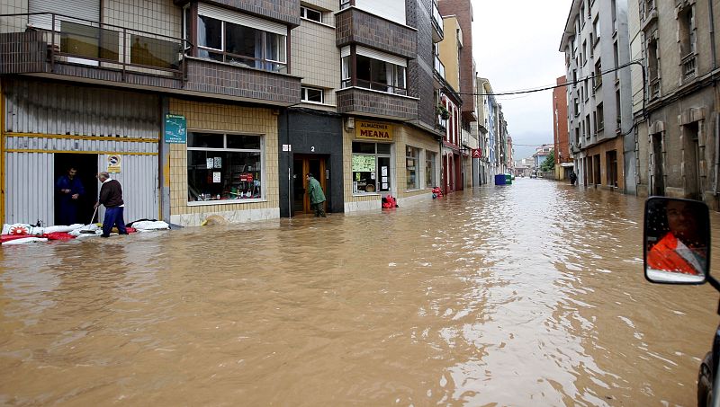 Los habitantes de Villaviciosa, tratan de proteger sus casas y sus negocios del agua que ha inundado las calles del municipio asturiano.