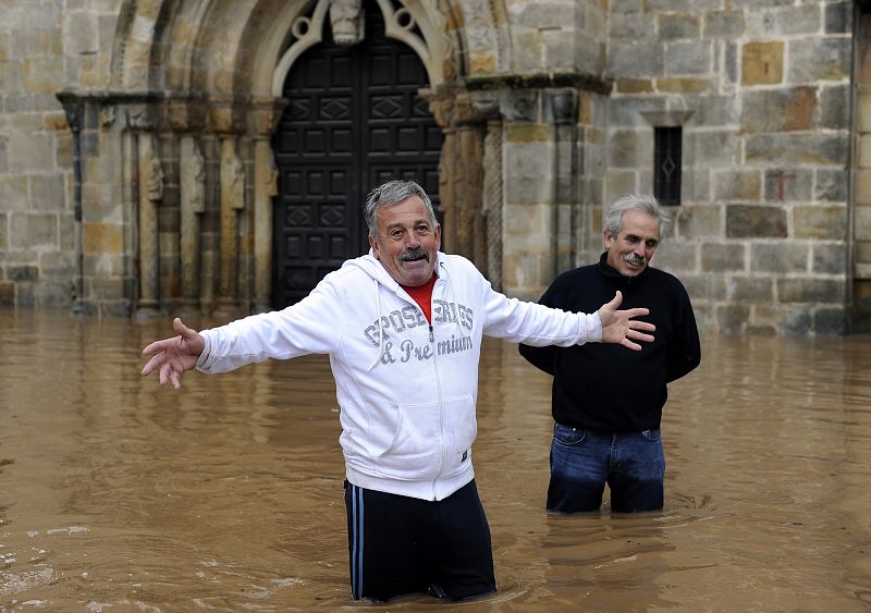 Two men stand on a flooded street in Villaviciosa