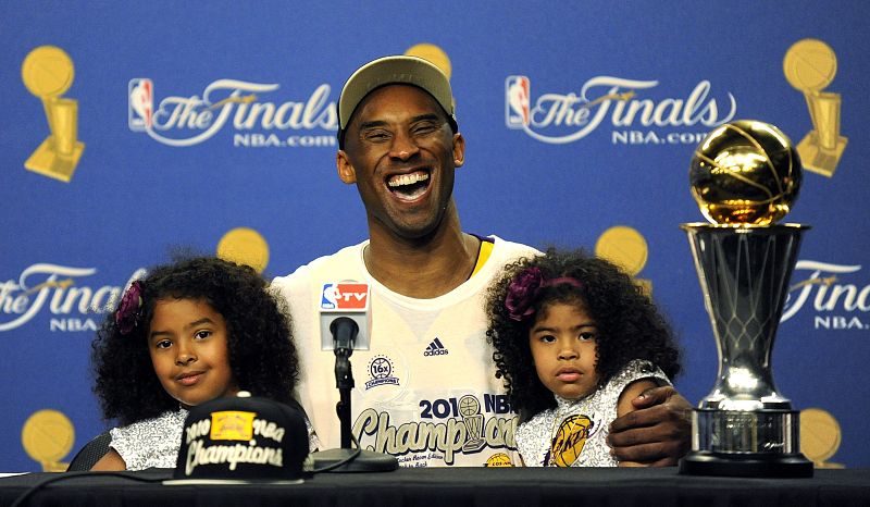 Kobe Bryant sonríe junto a sus hijas durante una conferencia de prensa junto al trofeo al jugador mas valioso del juego (MVP).