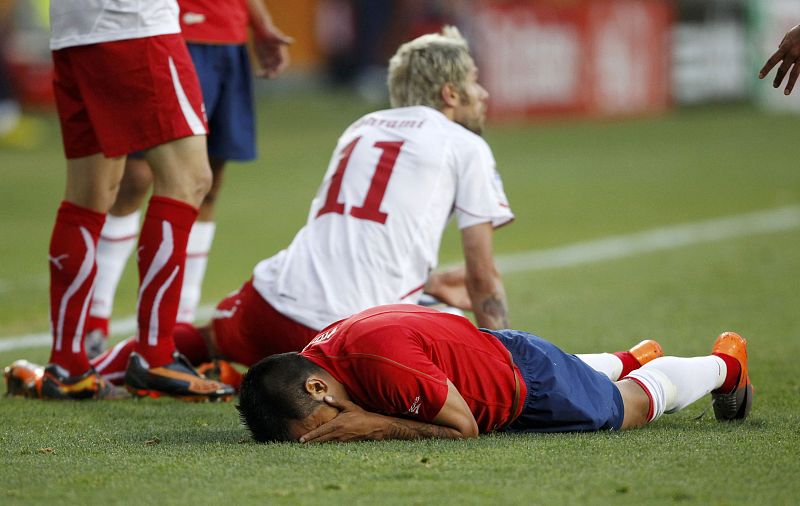 Chile's Vidal lies on the ground clutching his face as Switzerland's Behrami looks on during a World Cup match at Nelson Mandela Bay stadium in Port Elizabeth