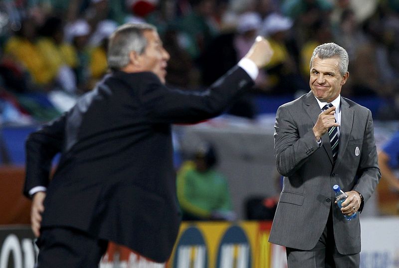 El entrenador de Uruguay Tabarez da instrucciones a sus jugadores mientras gestualiza el técnico mexicano Aguirre.