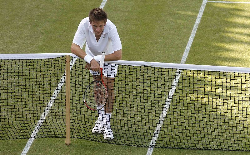 El francés Nicolas Mahut apoyado en la red demuestra su cansancio físico durante un partido del torneo de Wimbledon 2010